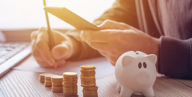 Savings, finances, economy and home budget calculations. Close up of man doing calculations and writing notes at home.