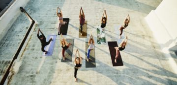 Overhead view of yoga class in warrior pose while practicing on rooftop